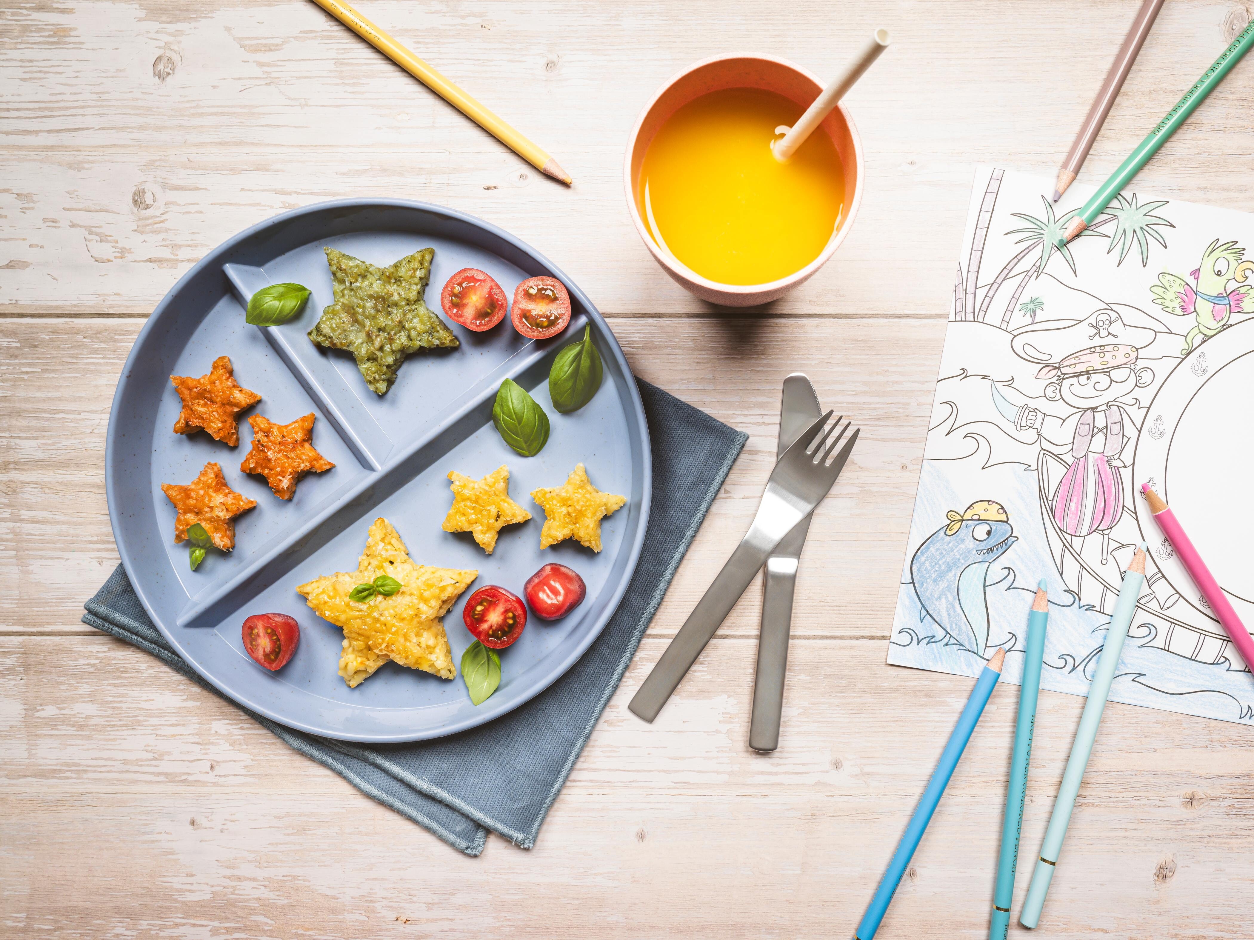 Bunte Risottosterne Ein Teller mit Essen, einem Getränk und Bleistiften.