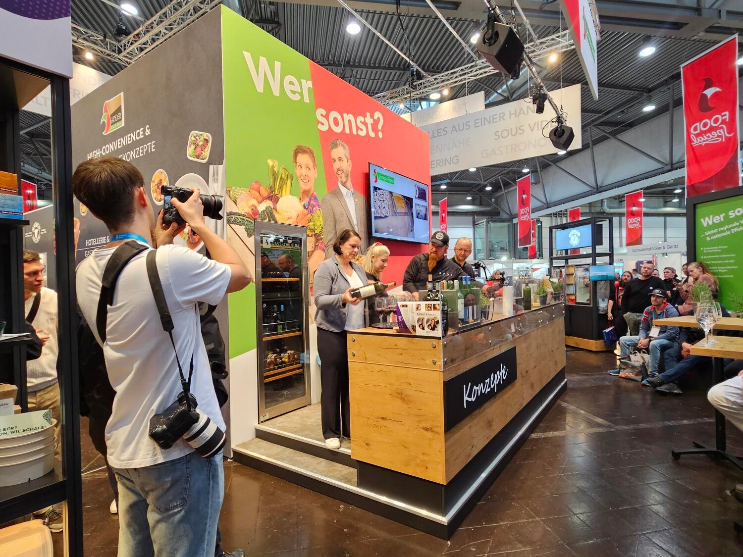 Eine Gruppe von Menschen in einem Raum, darunter Männer und Frauen, die stehen und miteinander interagieren.